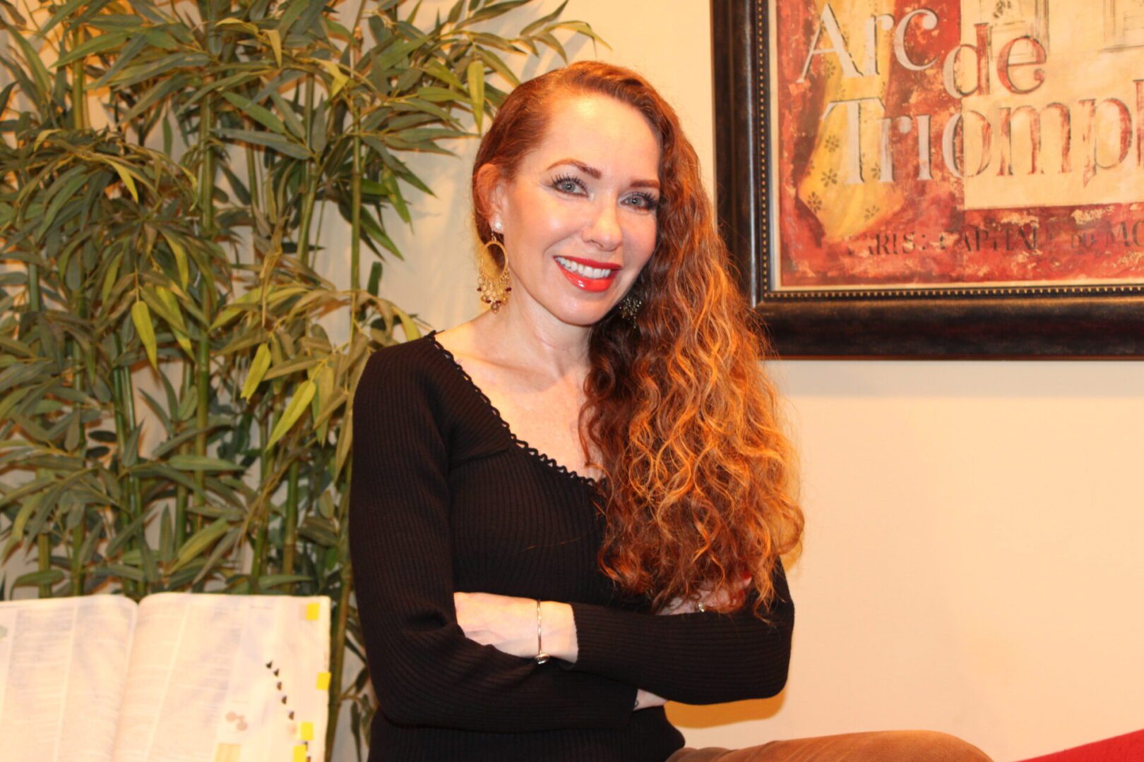 Woman with long red hair smiling confidently indoors.